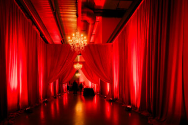 Upscale drape hallway with dramatic vibe, chandeliers, and up-lighting